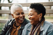 © Trinette Reed - Black lesbian couple connecting on bench in park outdoors. Generative AI...