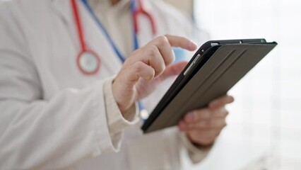 Wall Mural - Young hispanic man doctor using touchpad at clinic