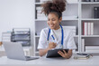 © David - Happy doctor Portrait of young African American woman nurse or doctor smilingusing a laptop writing content at consultation
