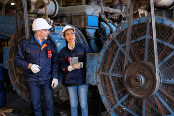 Two technical workers working in a maintenance shop checking heavy engine industry factory 
