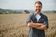 © Serhii - Happy farmer proudly standing in a field. Combine harvester driver going to crop rich wheat harvest. Agronomist wearing flannel shirt, looking at camera on a farmland