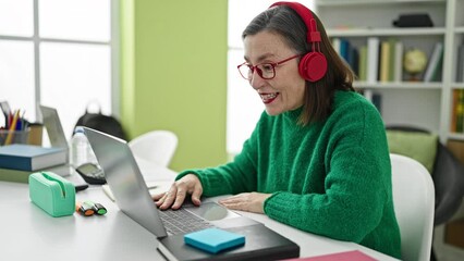 Poster - Mature hispanic woman with grey hair having video call sitting on table at library