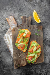 Wall Mural - sandwich with cream cheese, salmon, avocado, cucumber, tomato and greens on a light background. Keto breakfast or brunch. banner, menu, recipe place for text, top view