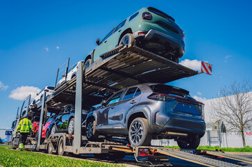 car carrier trailer transports cars on highway at blue sky background.