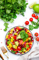 Wall Mural - Spicy salad with sweet corn, red beans, avocado, jalapeno, cherry tomatoes, red onion and cilantro. White table background, top view