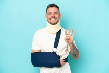 Wall Mural - Young caucasian man wearing a sling  and neck lace isolated on blue background happy and counting four with fingers