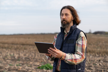 Wall Mural - Farmer with digital tablet on an agricultural field. Smart farming and digital agriculture	