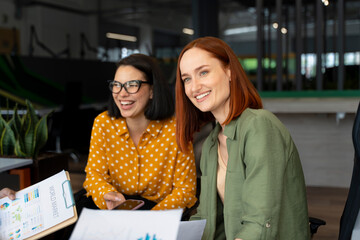 Group of European successful smiling businesswomen, colleagues working together in modern office.