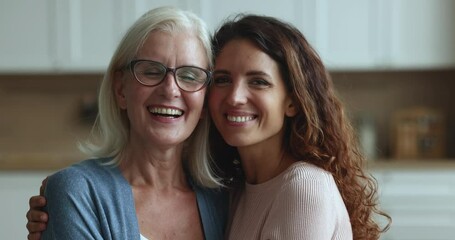 Wall Mural - close up portrait of two generational women. hispanic female hugs her caucasian aunt in glasses smil