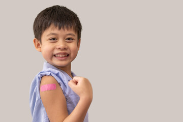 Portrait of happy smile vaccinated little asian kid boy children ages 5 to 11 years old posing show arm with medical plaster after Injection vaccine Covid-19 protection.coronavirus vaccination kid