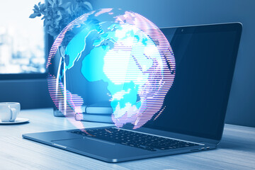 Aufkleber - Close up of workplace with laptop and glowing digital globe hologram on blurry background. Digital world, global hacking protection and hud concept. Double exposure.