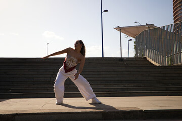 Wall Mural - Latin woman, young and beautiful dancing modern dance in the street and makes different expressions and postures. Concept dance, hip hop, dance, art, action, beauty, youth art.