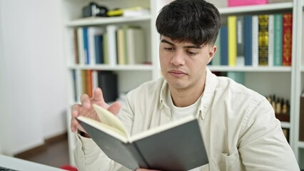 Sticker - Young hispanic man student reading book sitting on table at library university