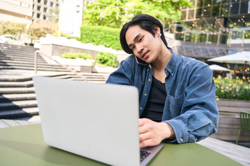 Wall Mural - Busy confident asian man using laptop communication, having mobile phone call