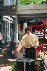 Wall Mural - Vertical view of handsome asian man wearing stylish sweater looking at laptop