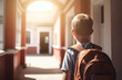 a schoolboy with a backpack walking along the school corridor or entering the school, back view. School concept, back to school, end of vacation