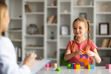 child development specialist lady having session with cheerful little girl