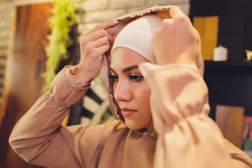 Portrait of positive pretty young Arabian woman in pink headscarf touching face with hand.