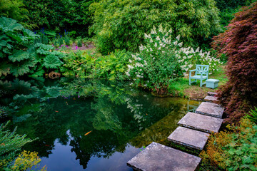 Wall Mural - A chair and table await in a beautiful serene garden by a pond with fish