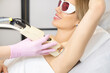 Young smiling beautiful woman getting armpit laser hair removal procedure. the concept of skin and body care in the spa salon. permanent hair removal.