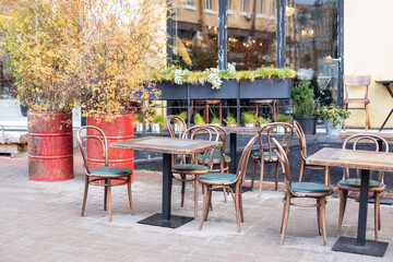 Wall Mural - Empty cafe with terrace with tables and wooden chairs. Street vintage exterior of restaurant. Furniture for coffee shop in street in Europe. Typical view of Parisian street with tables of cafe	