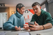 © Miljan Živković - teenage boy and mature caucasian woman sit together at the kitchen at home talk mother and son or relatives support solving problem share experience and opinion boy hold mobile phone smartphone