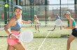 Two young motivated female padel players playing together in court