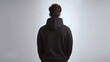 Young man from behind wearing a black hooded sweatshirt. Black hoodie mockup. Boy with modern short hair. Background with smooth and clean space with copy space. Generative ai.