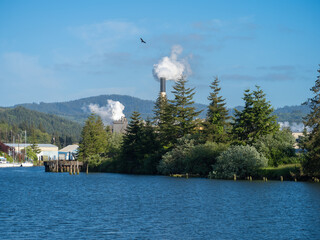 Poster - Logging Industry along the Yaquina River with a large smokestack with smoke or steam billowing out near the Oregon coast.
