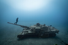 Man In Diving Suit Stands On Tank Underwater