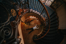 Man In White Shirt And Black Pants Lying Down Between Spiral Staircase