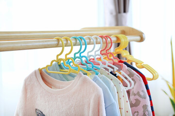 Hangers with clothes hang on a wood rack in house