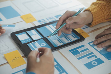 Close up ux developer and ui designer brainstorming about mobile app interface wireframe design on table with customer breif and color code at modern office.Creative digital development agency
