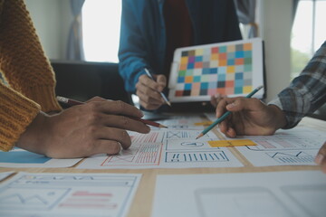 Close up ux developer and ui designer brainstorming about mobile app interface wireframe design on table with customer breif and color code at modern office.Creative digital development agency