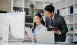 © laddawan - Asian business colleague business presents and explains and using laptop and tablet. Teamwork, financial marketing team, while sitting in office room.