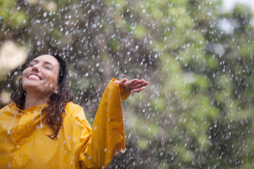 Wall Mural - Happy woman standing with arms outstretched in rain