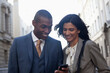 © KOTO - Smiling business people text messaging with cell phone