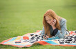 Woman using cell phone on blanket in park