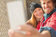 Couple taking self-portrait with camera phone next to chain link fence