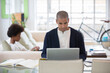 © KOTO - Man using laptop at desk in living room