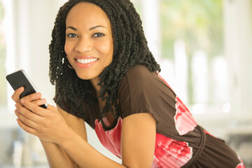 Wall Mural - Close up portrait of smiling woman holding cell phone