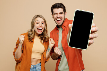 Wall Mural - Young couple two friends family man woman wear casual clothes hold in hand use mobile cell phone with blank screen workspace area do winner gesture together isolated on pastel plain beige background.