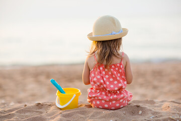 baby girl is sitting on beach and playing in sand in summer. holidays with children