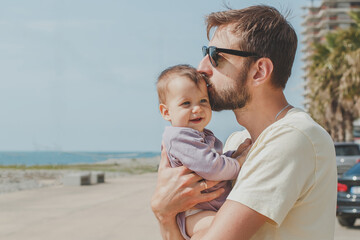 close-up portrait of dad and little cute daughter 8 months old on the seashore in summer on a sunny day, the concept of paternity and father's day holiday