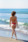 Fototapeta  - Calm woman walking on sandy seashore during summer vacation