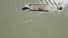 Overhead Shot Of A Motor Boat Pulling A Barge Up The Frasier River In Vancouver, Canada