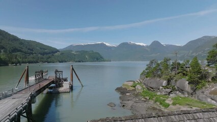 Wall Mural - Aerial slow movement around lake surrounded by mountains and growing trees