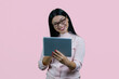 © DenisProduction.com - Cheerful smiling asian woman in glasses holding tablet pc. Isolated over pink background.
