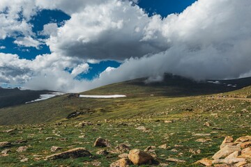 Sticker - Scenic view of green hills in a rural area enveloped in white puffy clouds