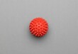 Close-up top view of a spikey red massage ball over the gray surface